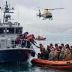 French coastguard rescue ship alongside an overcrowded migrant dinghy in the English Channel during a rescue operation