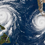 Satellite-style view of twin hurricanes Nolo and Polo churning over the Pacific Ocean near Hawaii and Baja California, Mexico.