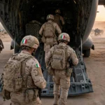 Italian soldiers boarding a military transport aircraft at a desert airbase in Iraq at dusk as the last troops withdraw