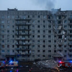 Damaged apartment building in Kharkiv, Ukraine, with emergency vehicles after a Russian guided bomb strike