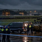 British police officers and an army bomb disposal vehicle at a cordon near RAF Fairford after five men were arrested.