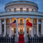 The White House South Portico at dusk with American and Chinese flags flying side by side during the Trump–Xi state visit