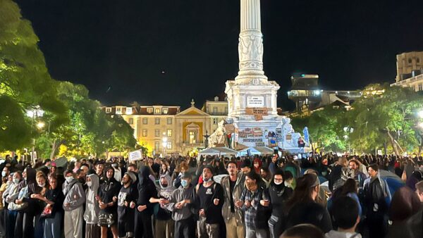 Night crowd at a housing protest in Rossio Square, Lisbon, October 2026, gathered beneath the Dom Pedro IV column.