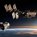 International Space Station with a departing SpaceX Crew Dragon capsule above the Earth's horizon at orbital dawn
