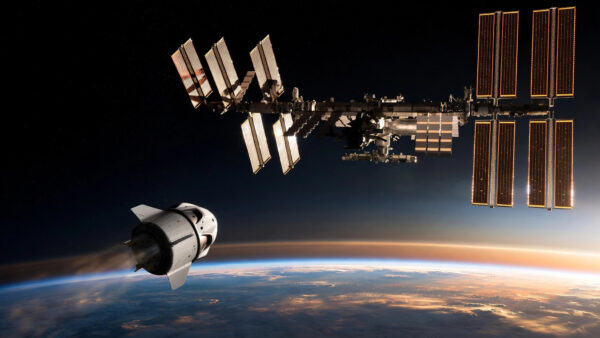 International Space Station with a departing SpaceX Crew Dragon capsule above the Earth's horizon at orbital dawn