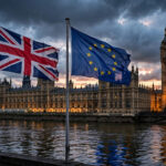 Palace of Westminster at dusk with Union Jack and European Union flags flying side by side above the River Thames