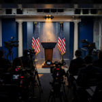The White House press briefing room with an empty podium, American flags and television cameras