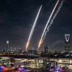Photorealistic editorial image of Riyadh's skyline at night with air-defence interceptor trails crossing the dark sky and emergency lights glowing near an airport, illustrating Monday evening's missile interceptions.
