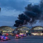 Smoke rising from King Khalid International Airport in Riyadh at dusk with fire engines on the tarmac after a missile strike