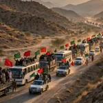 A convoy of trucks and buses carrying supporters with red and green flags on a highway in Khyber Pakhtunkhwa at dusk during the PTI long march toward Islamabad